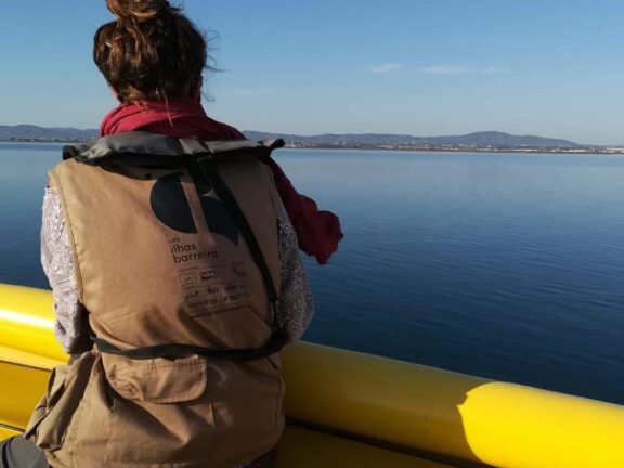voluntária LIFE Ilhas Barreira/SPIN num barco, com colete do projeto